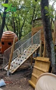 European pinecone outdoor playground with natural wooden cabins, rope bridges, and climbing structures