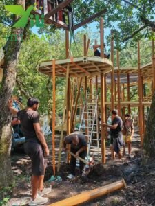 European pinecone outdoor playground with natural wooden cabins, rope bridges, and climbing structures