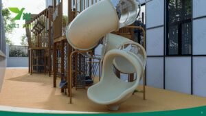 wooden playground bridge with rope tunnels, cabins, slides, and climbing nets in a school outdoor play area