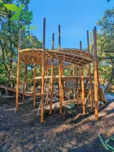 European pinecone outdoor playground with natural wooden cabins, rope bridges, and climbing structures