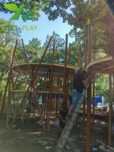 European pinecone outdoor playground with natural wooden cabins, rope bridges, and climbing structures
